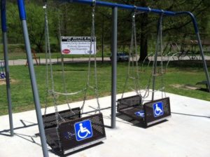 In this figure we observe two accessible swings for wheelchair users in a park.
