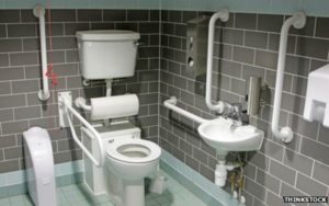 Accessible washroom with grab bars and adjustable commode